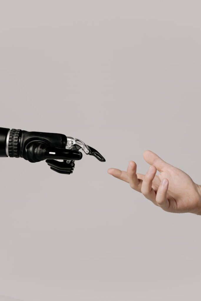 pexels-photo-6153343 A human hand reaching to touch a bionic prosthetic hand on a white background.