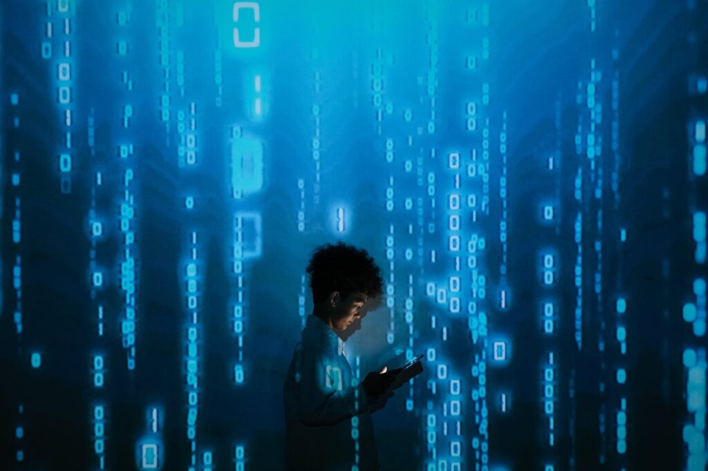 pexels-photo-9783812 Silhouette of a person using a smartphone surrounded by digital binary code projections.